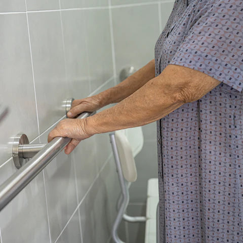 Older adult holding bathroom grab bars installed for safety