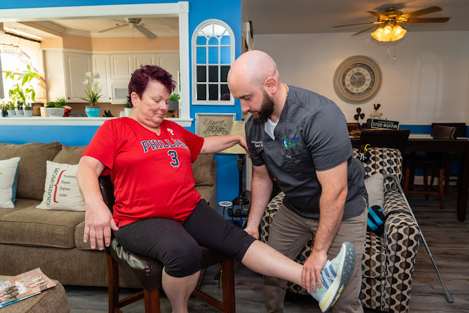 Physical therapist helping a patient with a knee exercise during an in-home visit